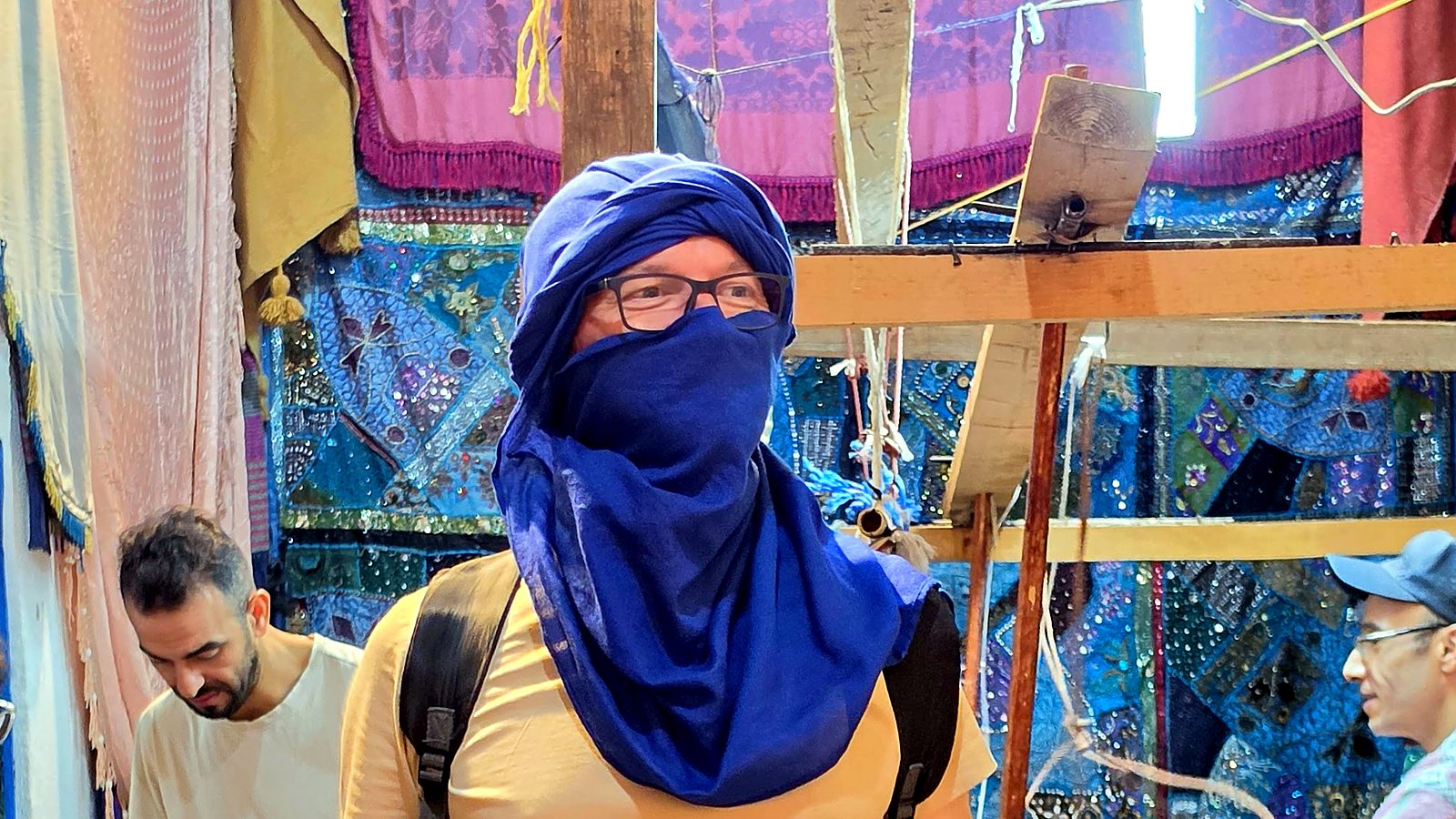 Član ekipe preizkuša modri turban v prodajalni s turbani